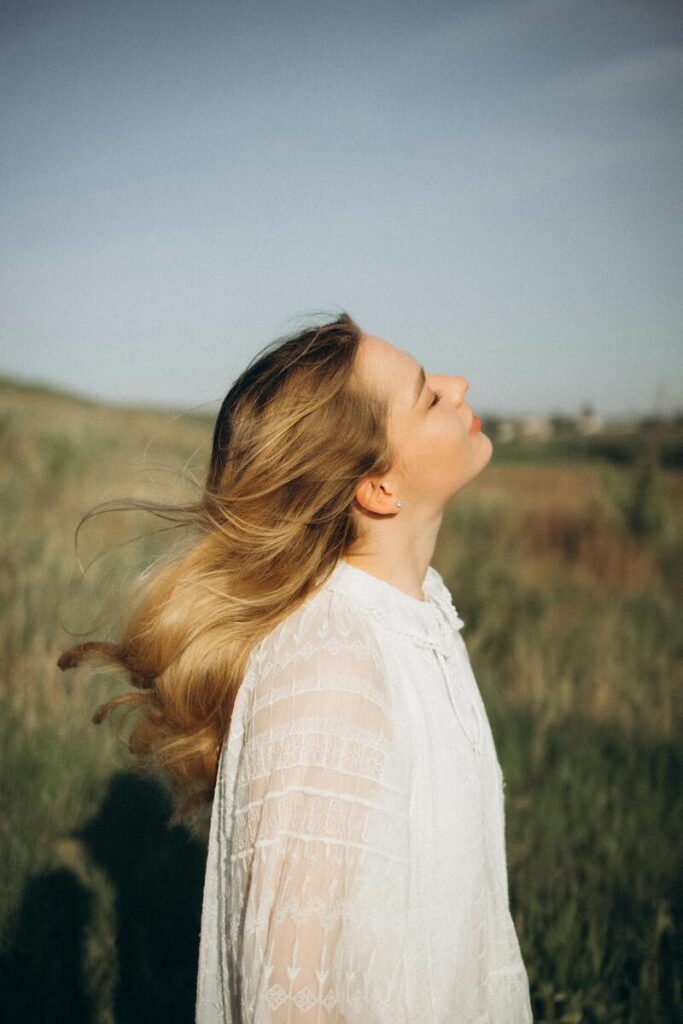 Donna all'aperto con capelli biondi al vento e sguardo di profilo verso l'alto