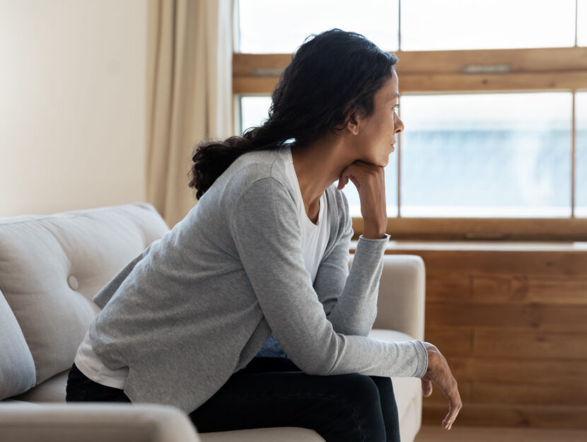 Donna triste sul divano in casa