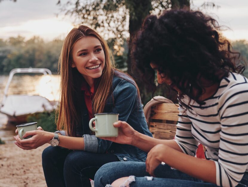 Due amiche parlano tra loro con una tazza di caffè in mano