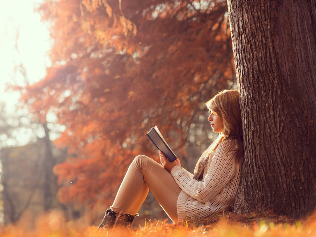 Donna legge libro autunno albero
