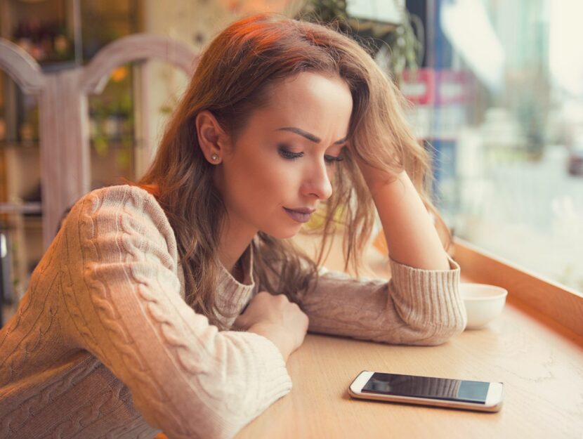 Ragazza guarda smartphone in attesa di messaggi