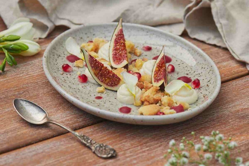 Dessert elegante con fichi, crema e fiori su un piatto rustico