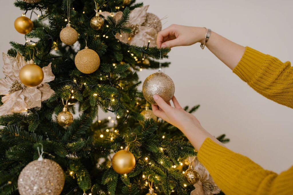 una ragazza sta appendendo palline dorate all'albero di natale