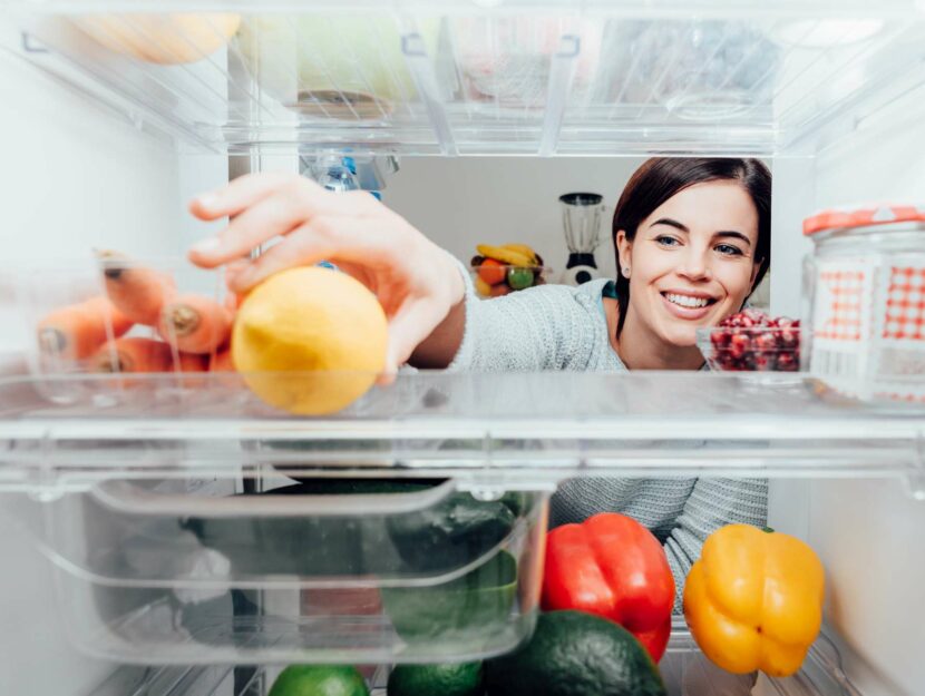 donna afferra un limone dal frigorifero