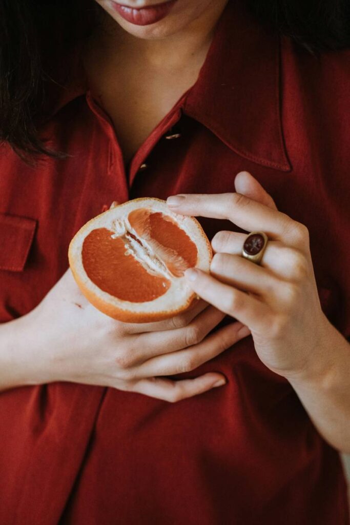 ragazza con un pompelmo in mano aperto