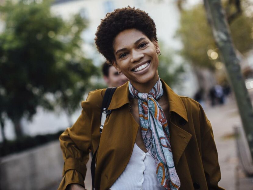 ragazza sorridente e alla moda passeggia per la strada