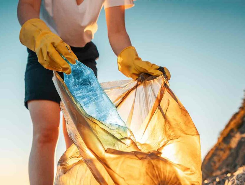 Zero waste: una donna raccoglie rifiuti su una spiaggia