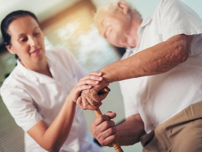 Infermiera aiuta uomo anziano malato di Parkinson