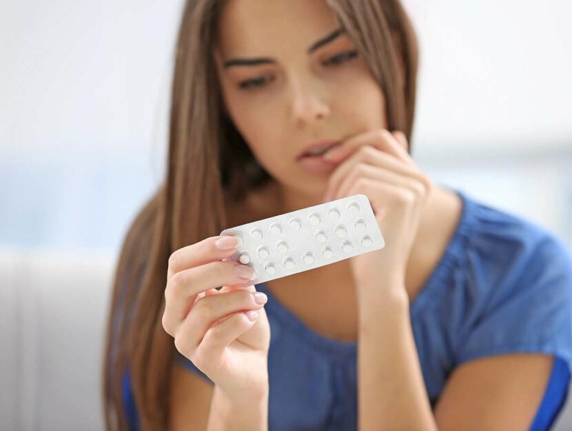 Giovane donna con pillola anticoncezionale