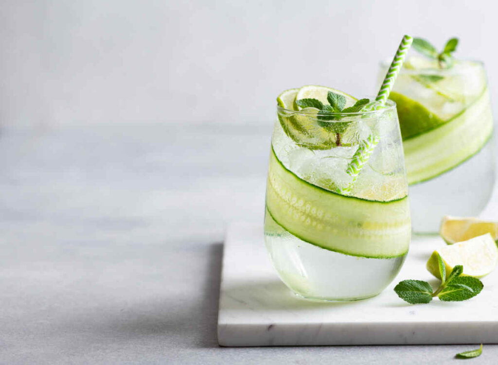 Bicchiere con acqua con cetrioli su tagliere