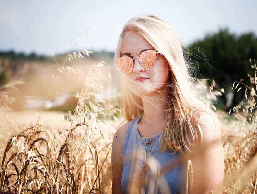 ragazza con occhiali da sole in un campo di grano