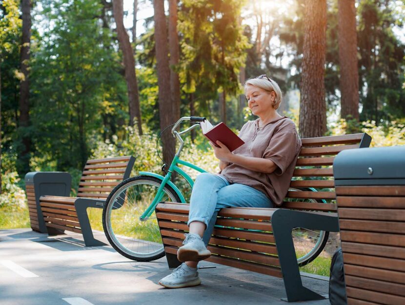 Donna in pensione legge un libro in un parco