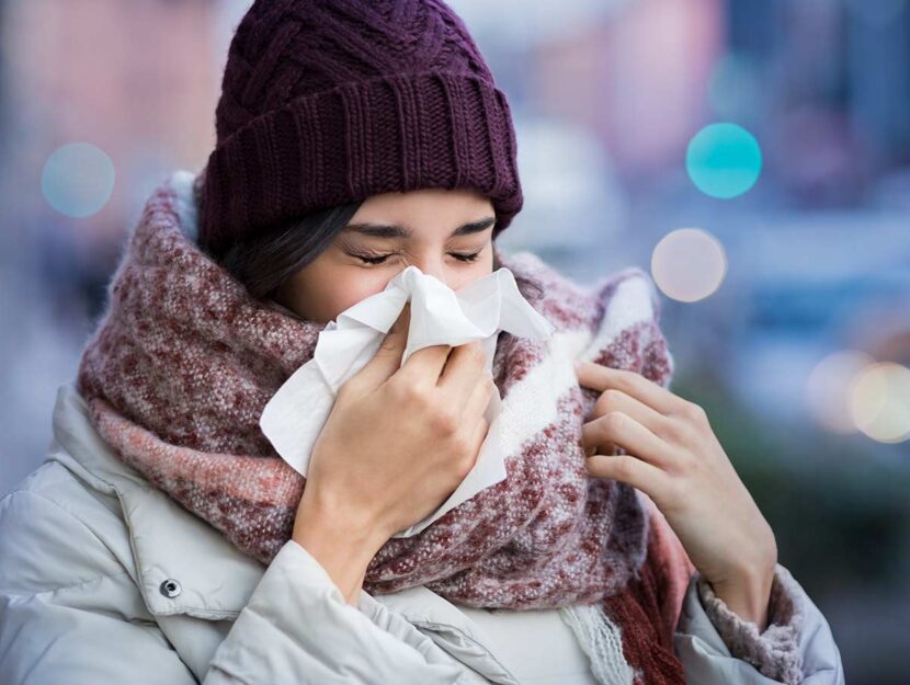 Giovane donna con raffreddore si soffia il naso