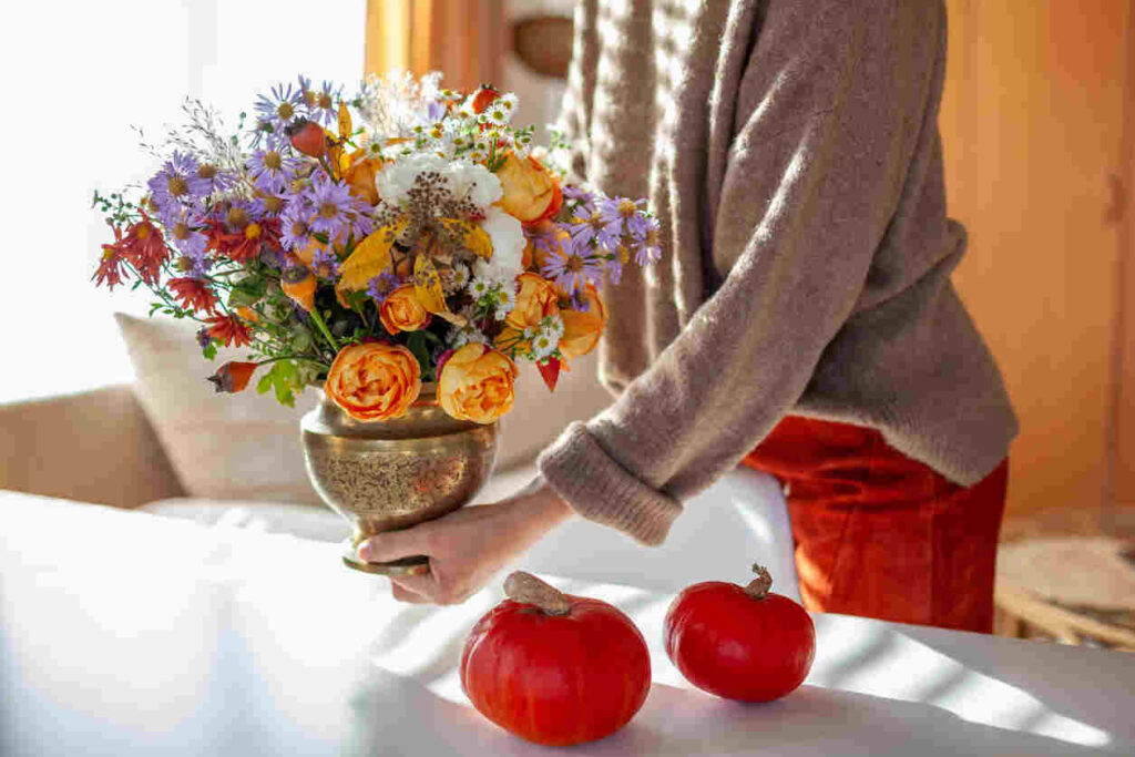 donna che mette bouquet di fiori sul tavolo con zucchette