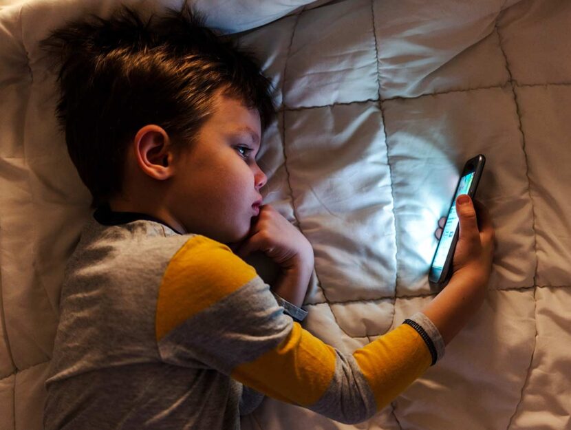 Bambino a letto con smartphone