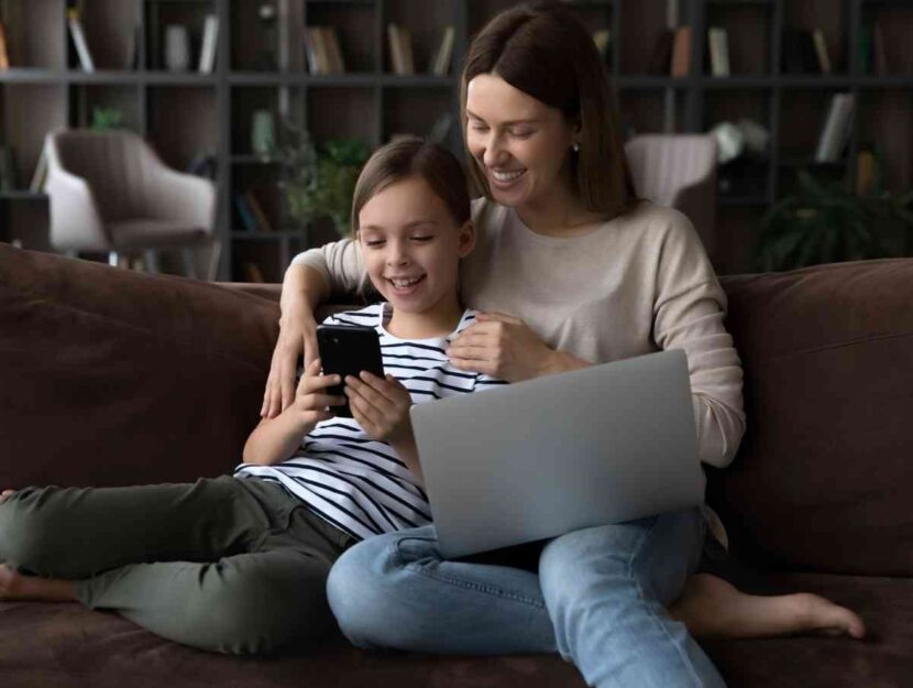 Una donna guarda lo smartphone con la figlia