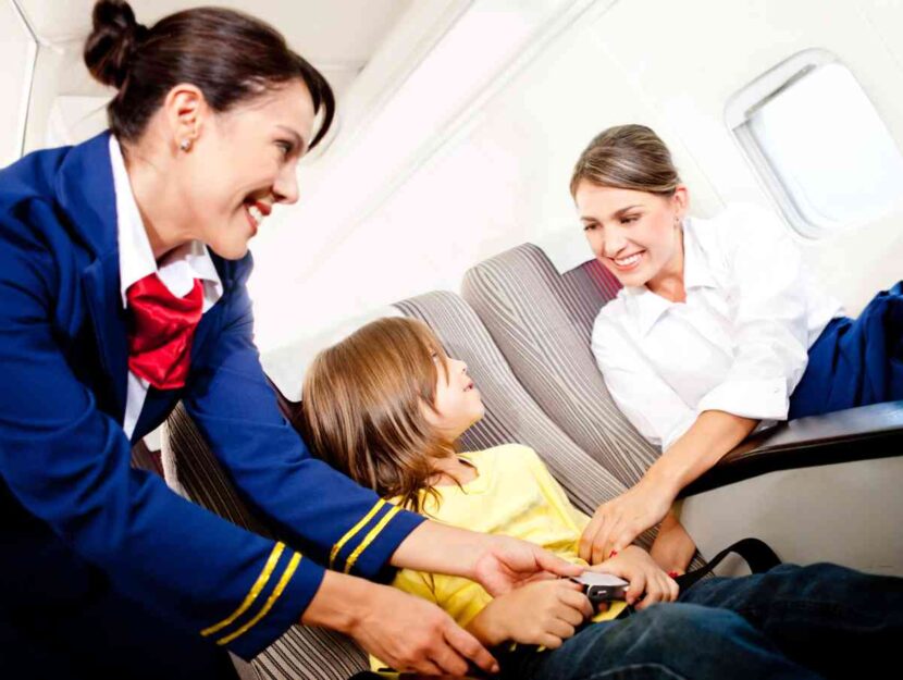 Una hostess aiuta una madre con il suo bambino in aereo