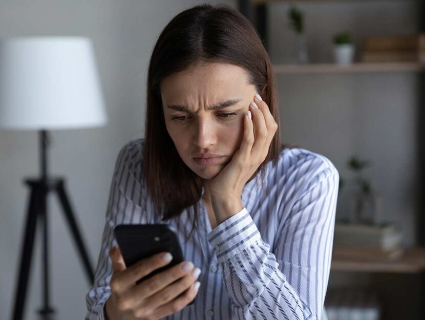 Giovane donna guarda lo smartphone con preoccupazione