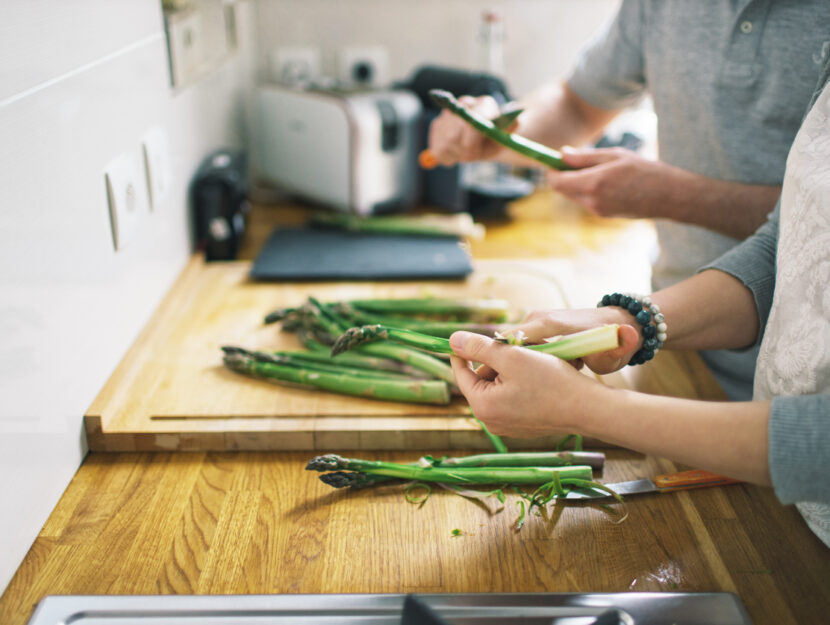 ragazzi che stanno pulendo gli asparagi su un tagliere