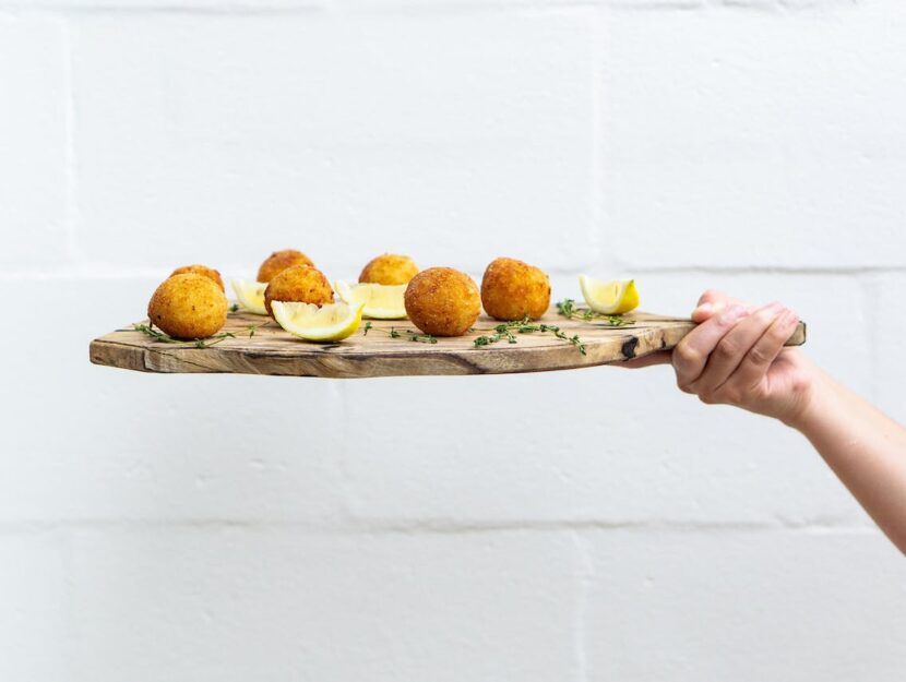 mano che porge un tagliere di arancini