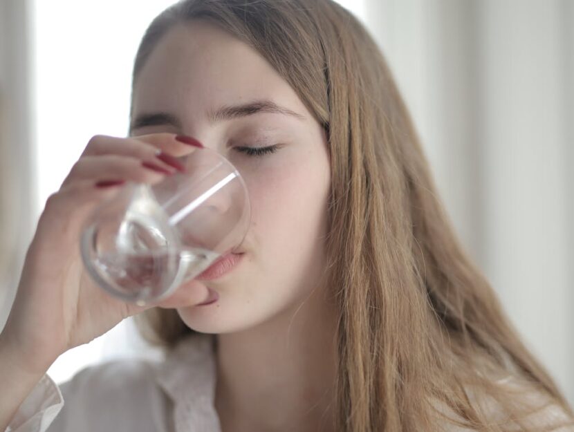 ragazza che beve un bicchiere d'acqua