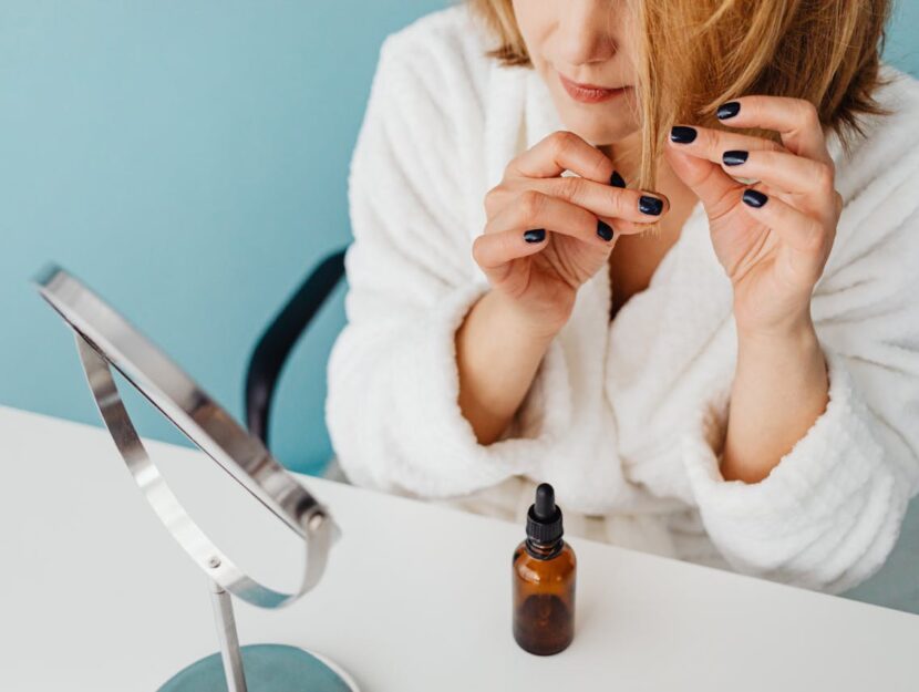 ragazza che si pettina i capelli allo specchio e utilizza oli