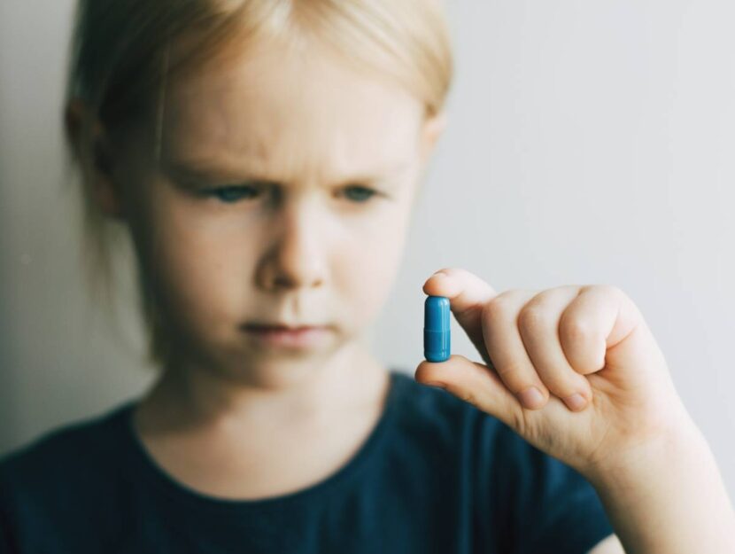Una bambina con una pillola in mano