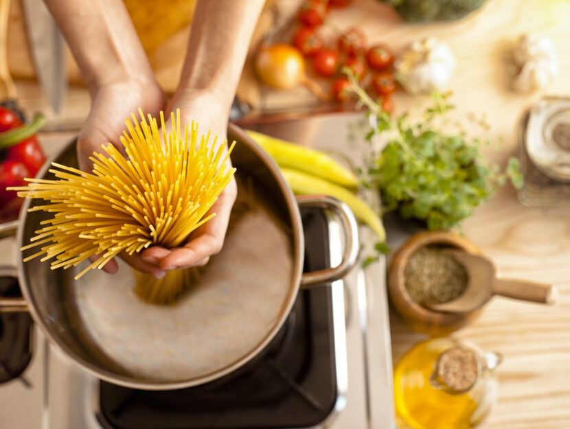 ragazza sta cucinando spaghetti in una pentola