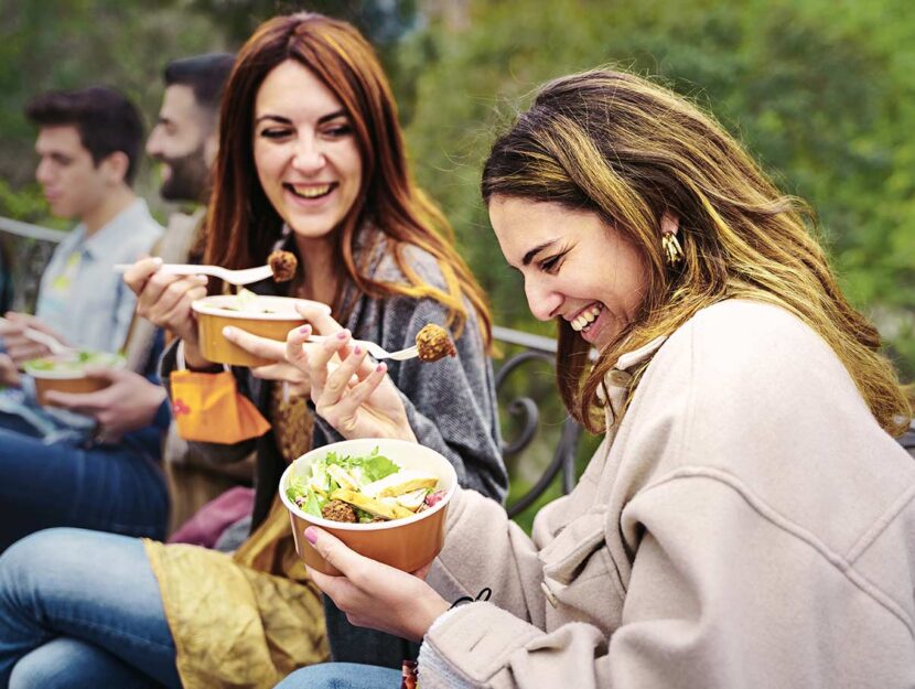 Giovani donne sorridono mangiando in pausa prabnzo