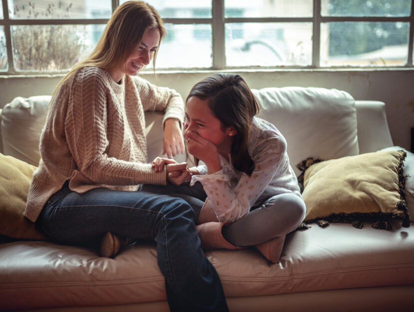 madre e figlia adolescente chiacchierano e ridono sul divano