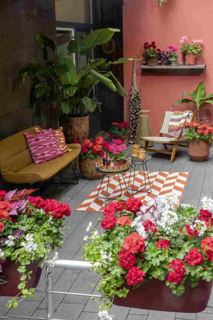 Balcone decorato con piante, con tavolo al centro, divano con cuscini e sedia