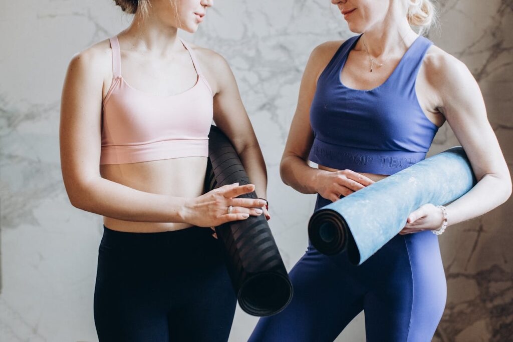 due ragazze in tenuta fitness con il loro tappetino yoga sotto il braccio