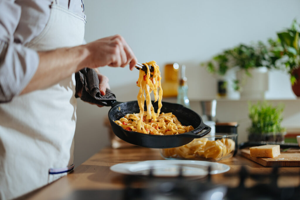 ragazza che sta spadellando la pasta
