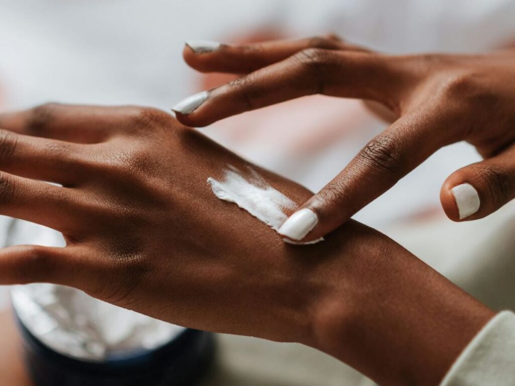 ragazza si spalma la crema sulle mani