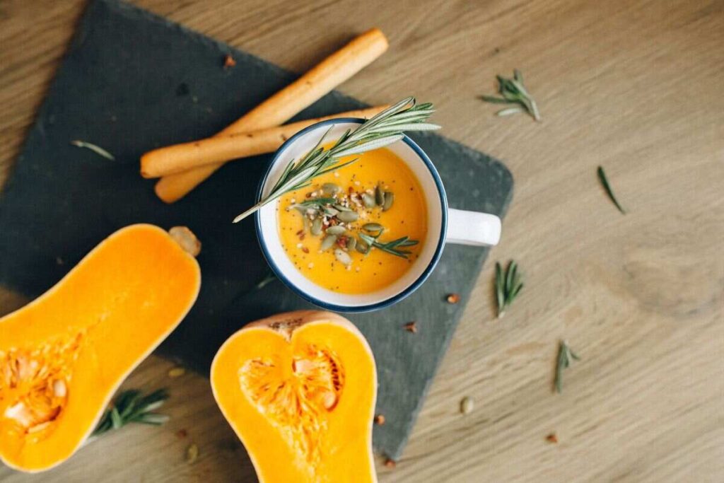 zucca a meta e bicchiere con crema di zucca, semi di zucca e rosmarino