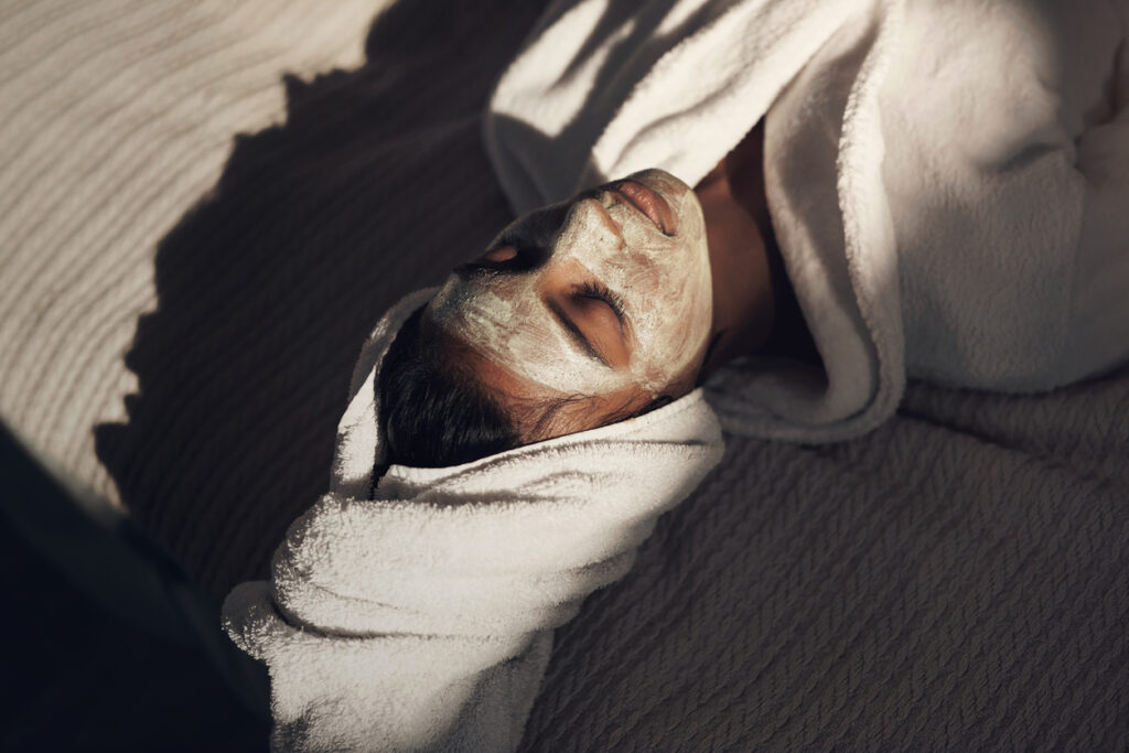 ragazza si riposa sul letto con una maschera sul viso