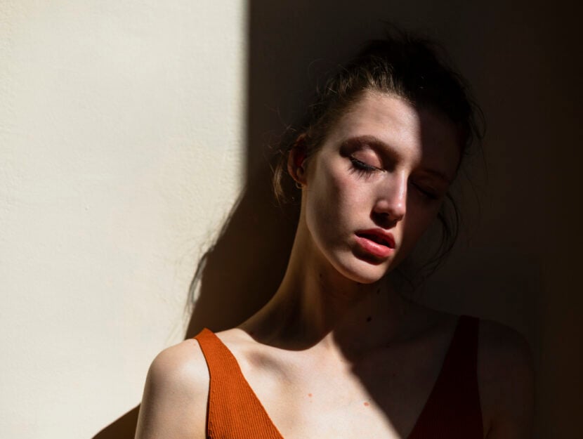 ragazza con gli occhi chiusi appoggiata al muro