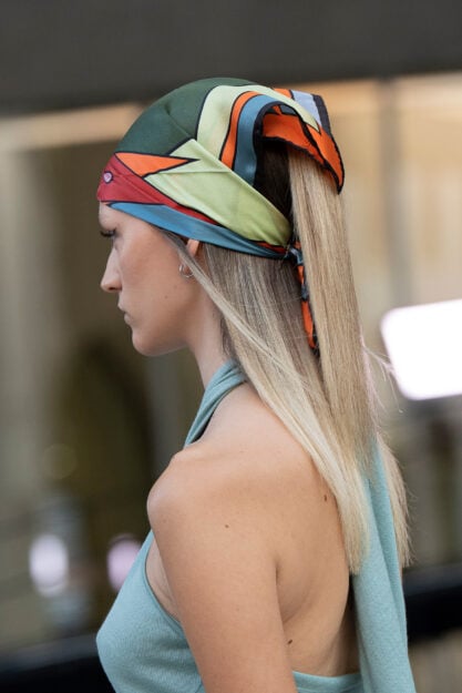 Come proteggere i capelli dal sole: ragazza lega foulard sulla testa