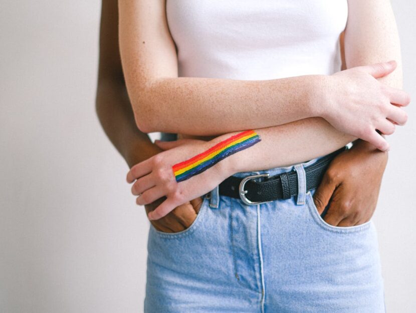 ragazze abbracciate con bandiera arcobaleno sul braccio
