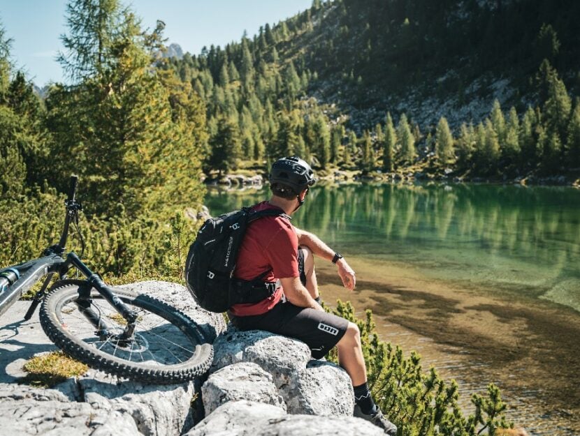 Un biker si riposa dopo la salita verso un lago alpino nella regione turistica di San Vigilio Dolomi