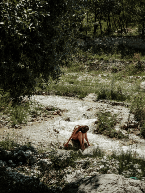 Ragazza fa il bagno in un torrente di montagna in una vacanza benessere