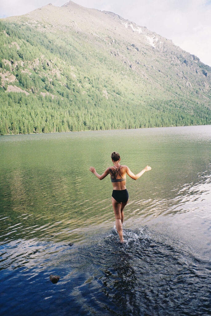 Ragazza fa il bagno in un lago di montagna in una vacanza benessere