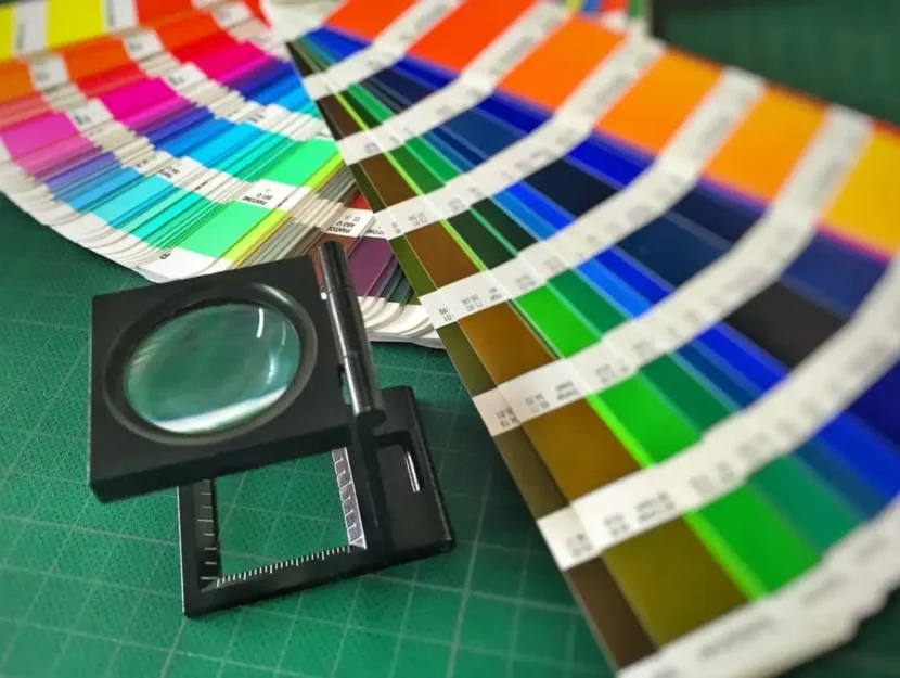 Immagine di colori e pantoni stasi su un tavolo e una lente per osservarli nel dettaglio