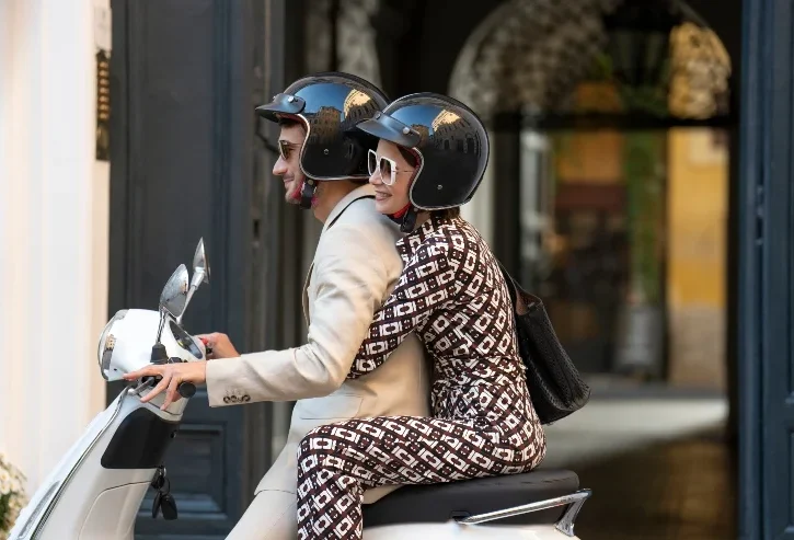 Lily Collins (Emily Cooper) e Eugenio Franceschini (Marcello) a bordo di una vespa bianca in una scena di "Emily in Paris 5"
