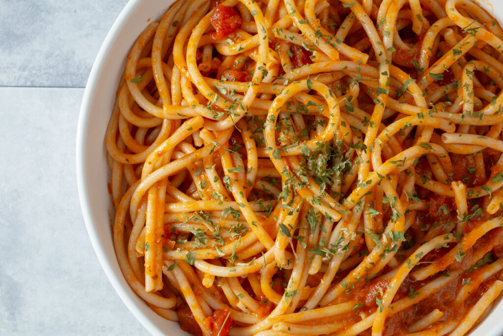 Perciatelli alla sorrentina con salsa di pomodoro e origano su piatto