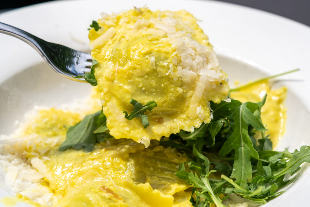 Piatto di ravioli con formaggio grattugiato e rucola 