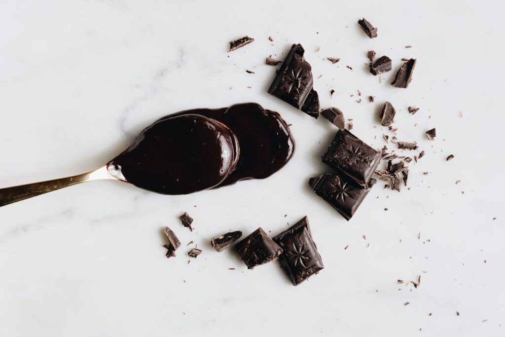 quadrati di cioccolata e cucchiaio con cioccolati posti sul tavolo