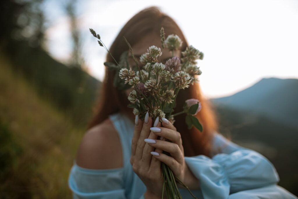 ragazza con fiori in mano che coprono il volto 