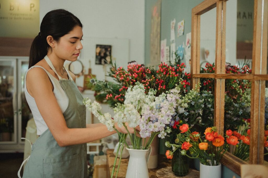 fioraia aggiusta fiori nei vasi in negozio