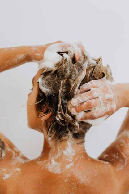 donna lava i suoi capelli mossi durante lo shampoo
